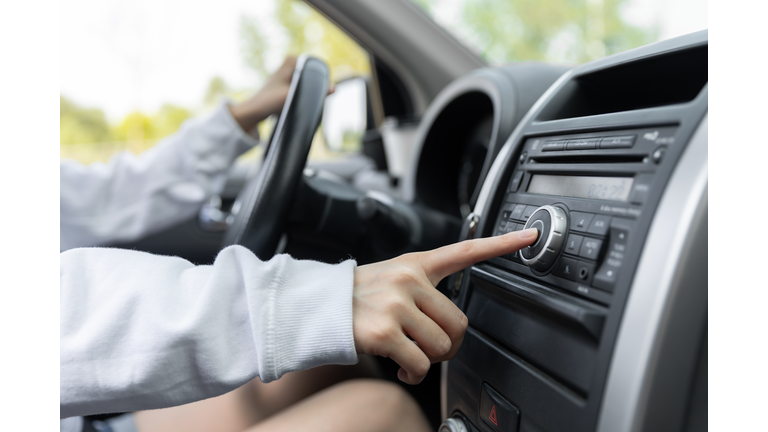 woman turning button of radio in car