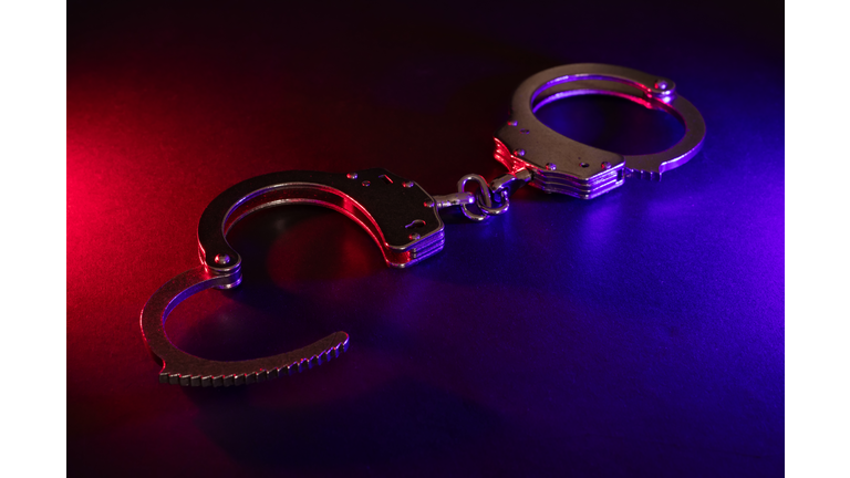 Closed handcuffs on the street pavement at night with police car lights high contrast image