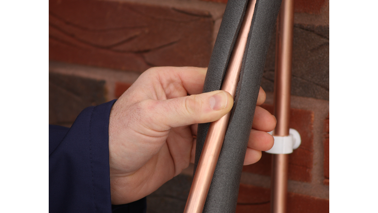 Plumber insulating a copper water pipe