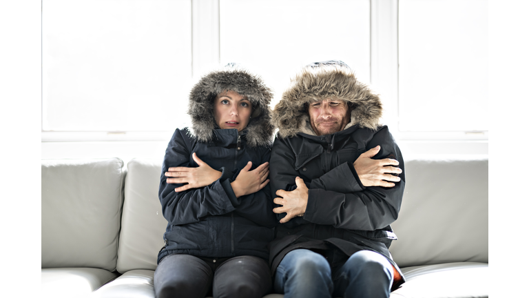 Couple have cold on the sofa at home with winter coat