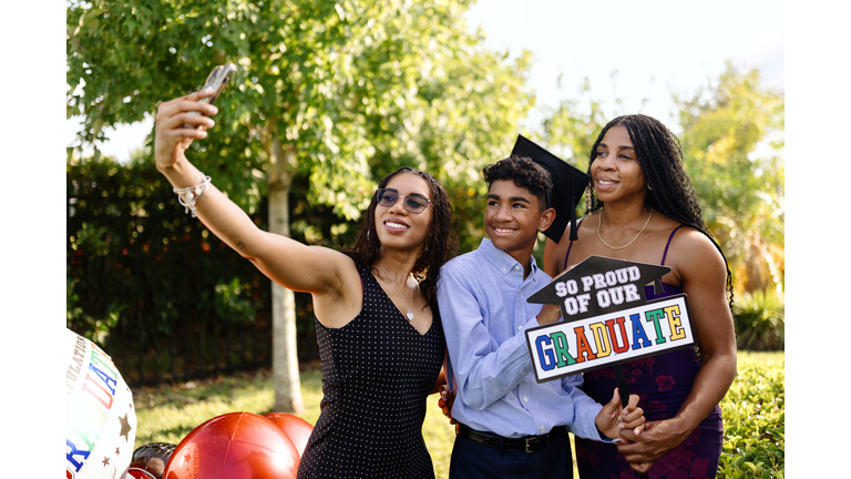 Smiling family taking selfies with a graduate