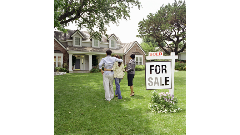 Real Estate Agent standing with couple in front of house