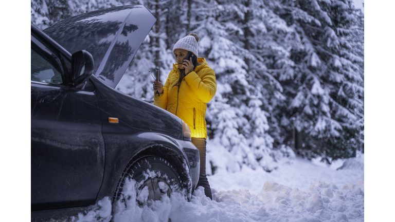 Winter car breakdown, woman calls for help.