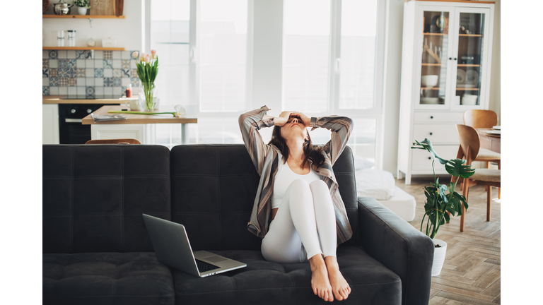 Depressed young woman sitting on sofa at home