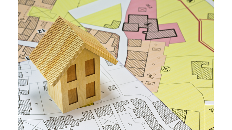 Construction industry and building permit concept with a residential area, cadastral map, General Urban Planning and wooden residential home model