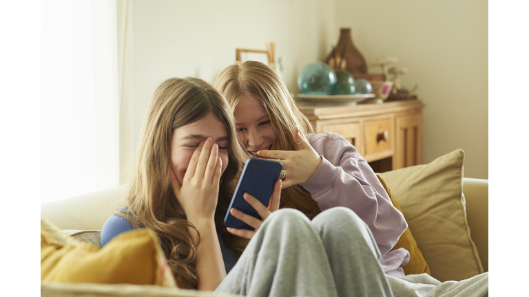 Teenage girls sitting on the sofa using a smart phone