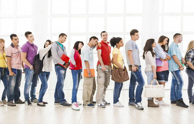 Group of bored students standing in a line and waiting.