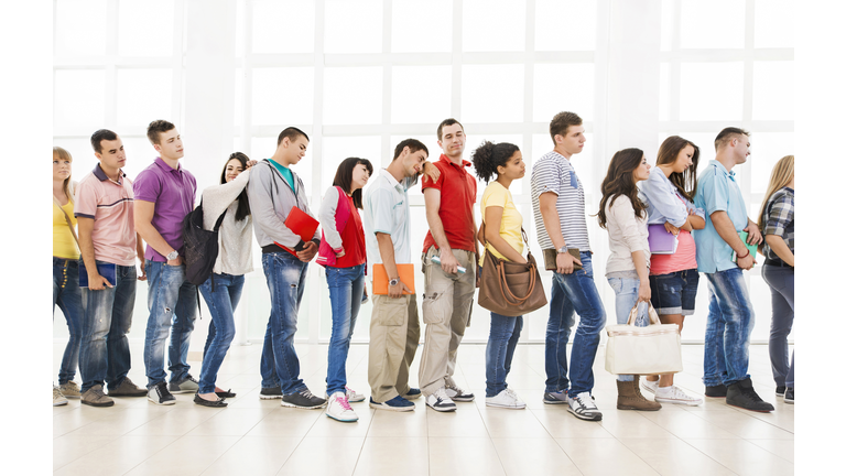 Group of bored students standing in a line and waiting.