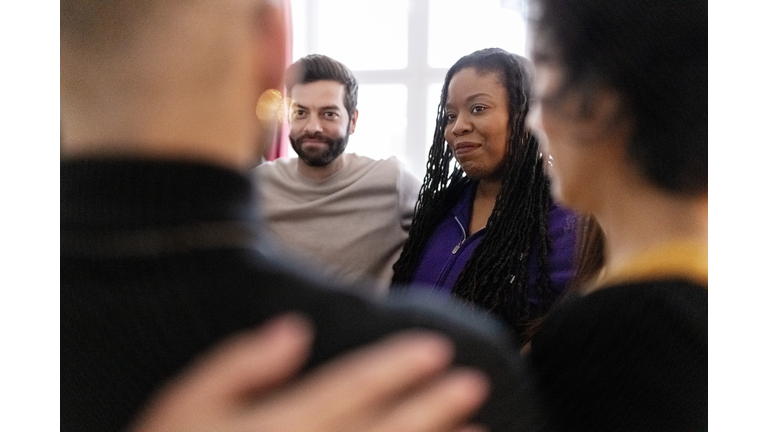 Diverse group of people standing in a huddle during therapy session