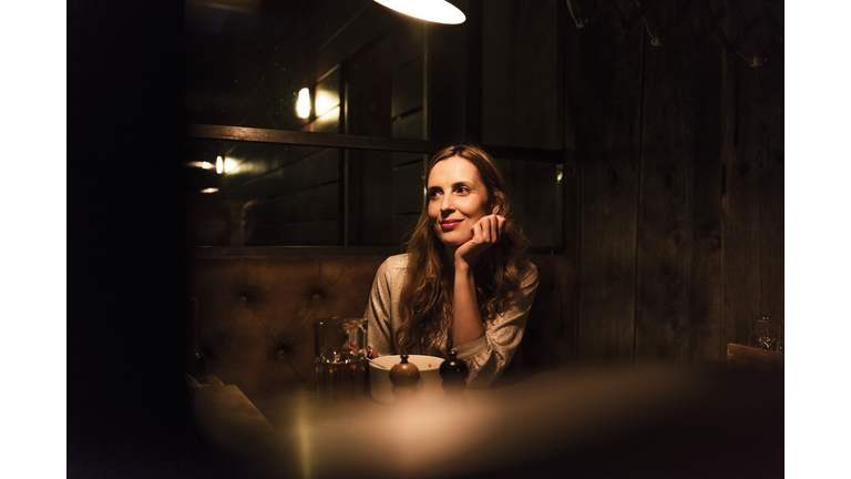 Smiling woman sitting at dining table looking sideways