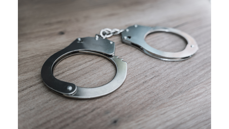 the concept of arrest and crime. handcuffs on a wooden table