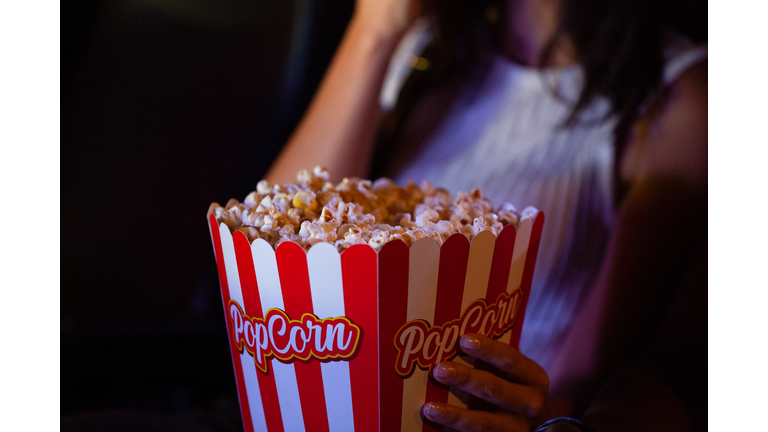 Unidentified person's hand holding a bucket of popcorn in movie theater