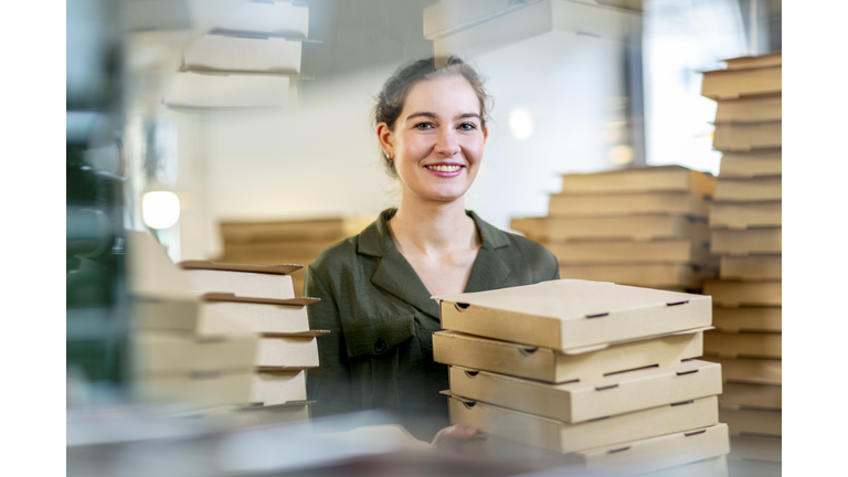 young and female small business owner with pizza boxes