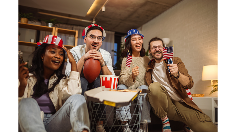 Multiracial group of friends watching rugby with American flags.