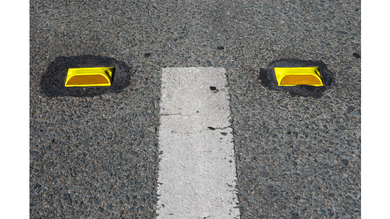 White dividing line and yellow plastic road reflectors on a city street