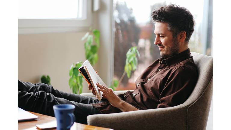 Young man reading a book at home