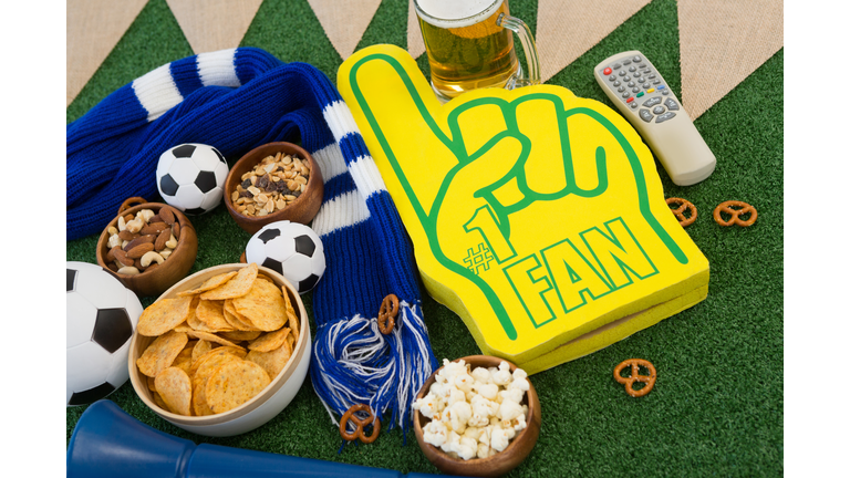 Foam hand, snacks and footballs on artificial grass