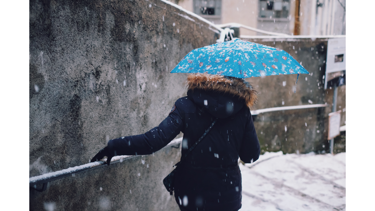 Girl with umbrella goes down the staircase while it snows
