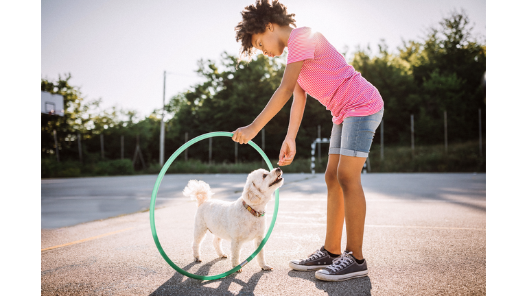 African girl playing with plastic hoop and her dog