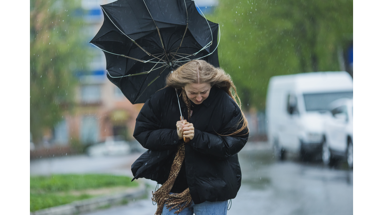 Blonde woman under umbrella. Storm weather. Torrential rain
