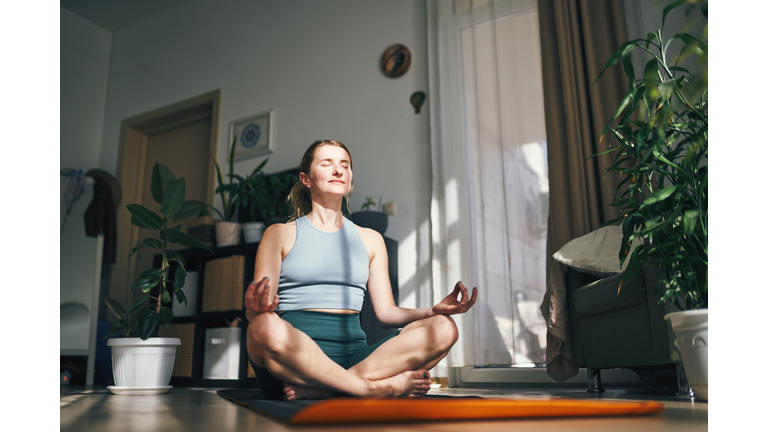 Woman enjoys a peaceful moment in meditation, embraced by the warmth of her home.