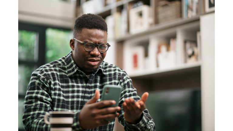 Young African American man having reading bad news on his smart phone