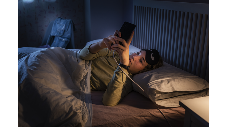 Teenage girl suffering sleeping disorders using smartphone at night