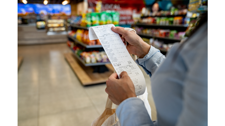 Woman shopping at a convenience store and checking her receipt