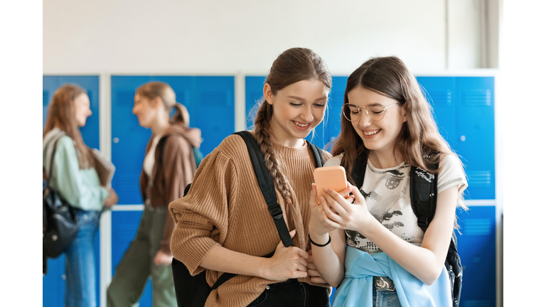 Teenage girls using smart phone in school corridor