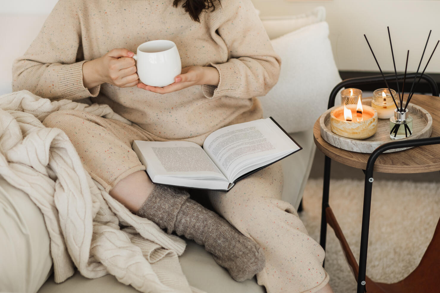 Close up of womans hands with mug of hot tea and book.