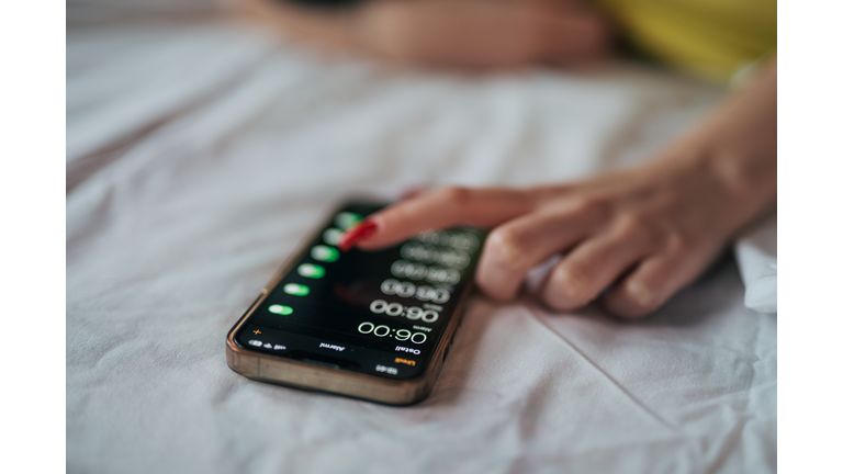 A young woman snooze an alarm on her phone in the morning