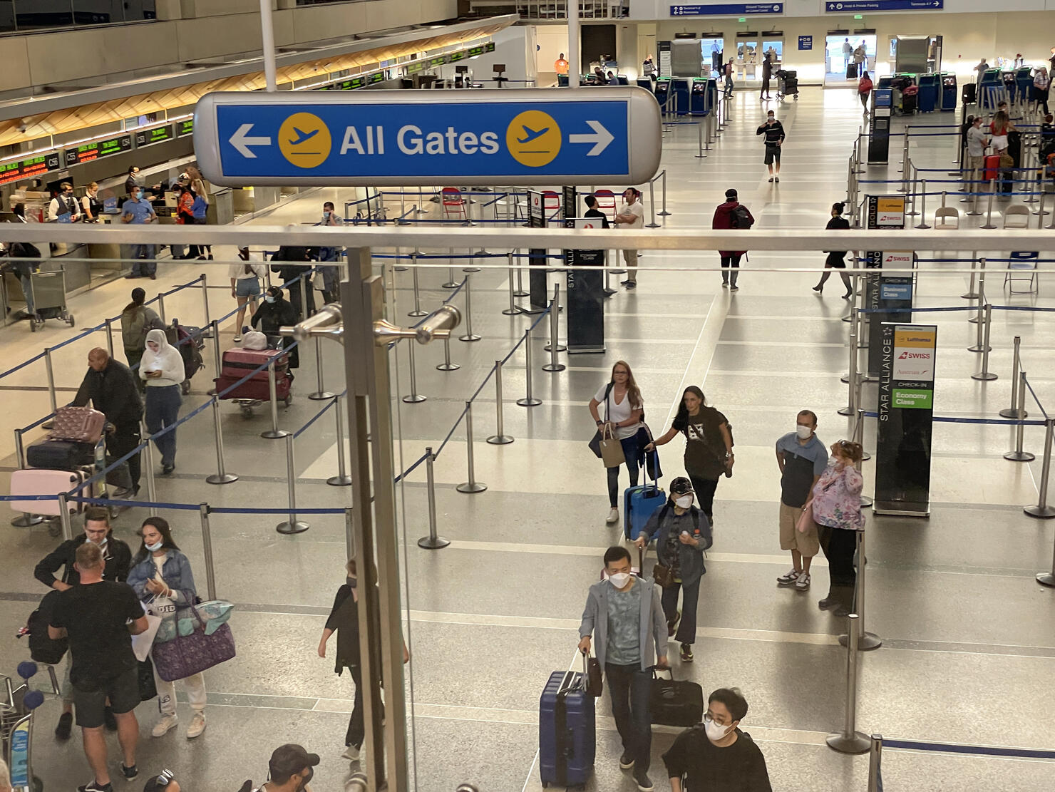 All gates sign at the airport with people waiting to check-in