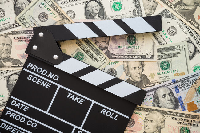 Cinema clapperboard on stack US dollars banknote bill background.