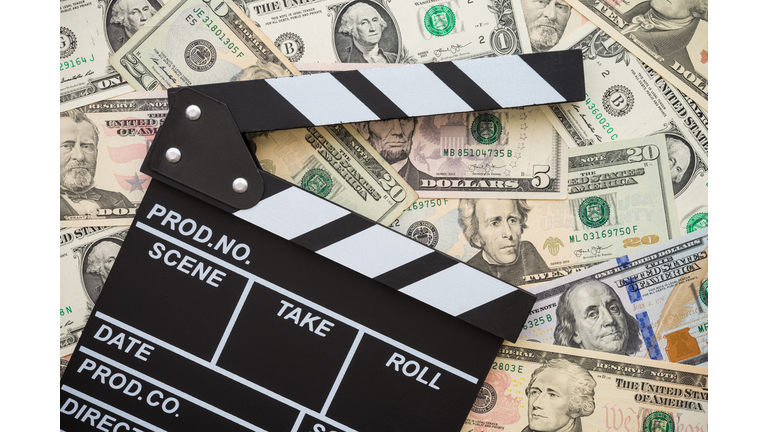 Cinema clapperboard on stack US dollars banknote bill background.