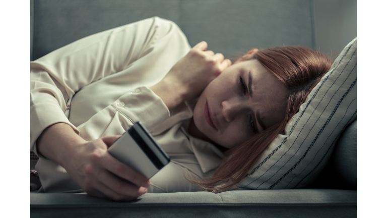 The girl is doomscrolling: sitting with a phone in her hands, a concentrated look, an expression of anxiety