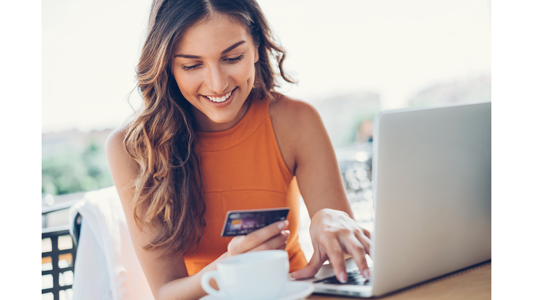 Smiling woman with credit card and laptop