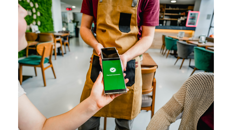 Woman paying with a smartphone in a café