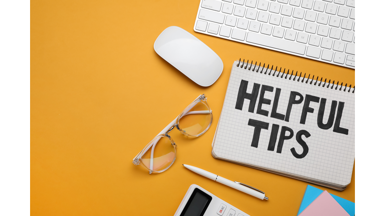 Helpful Tips. Flat lay composition with notebook and computer keyboard on orange background, space for text