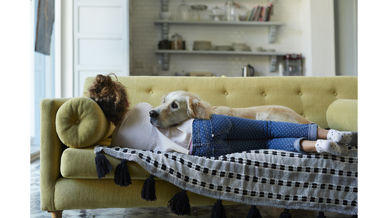 Girl sleeping on couch with her Golden Retriever dog