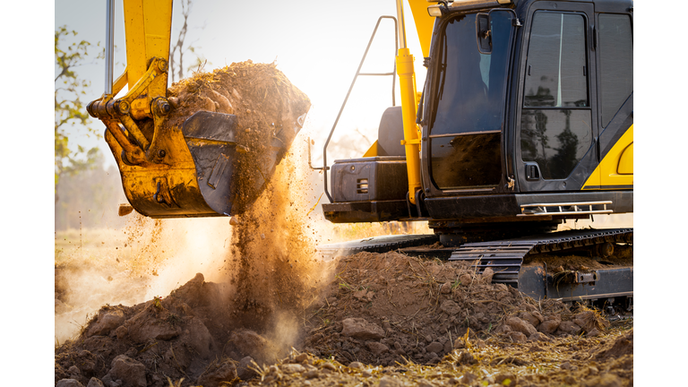 Close-up of excavator at construction site. Backhoe digging soil for earthwork and construction business. Excavating machine at work. Heavy machinery for earth moving and construction site development