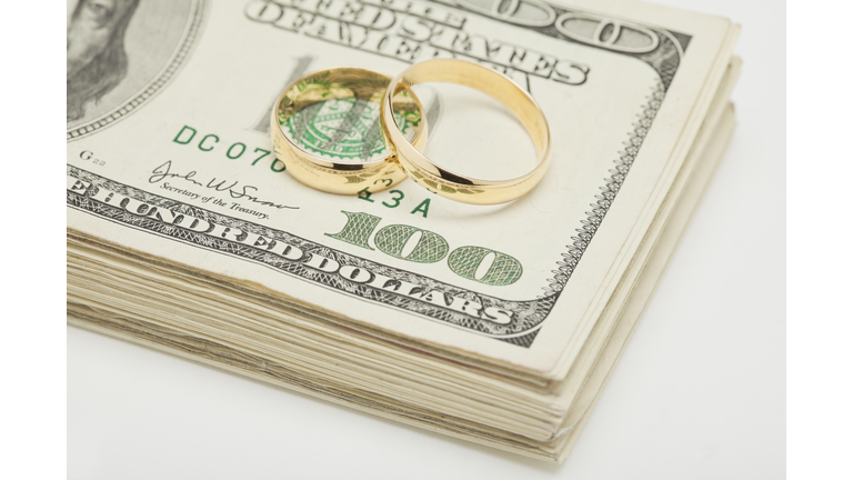 Studio shot of wedding rings on wad of banknotes