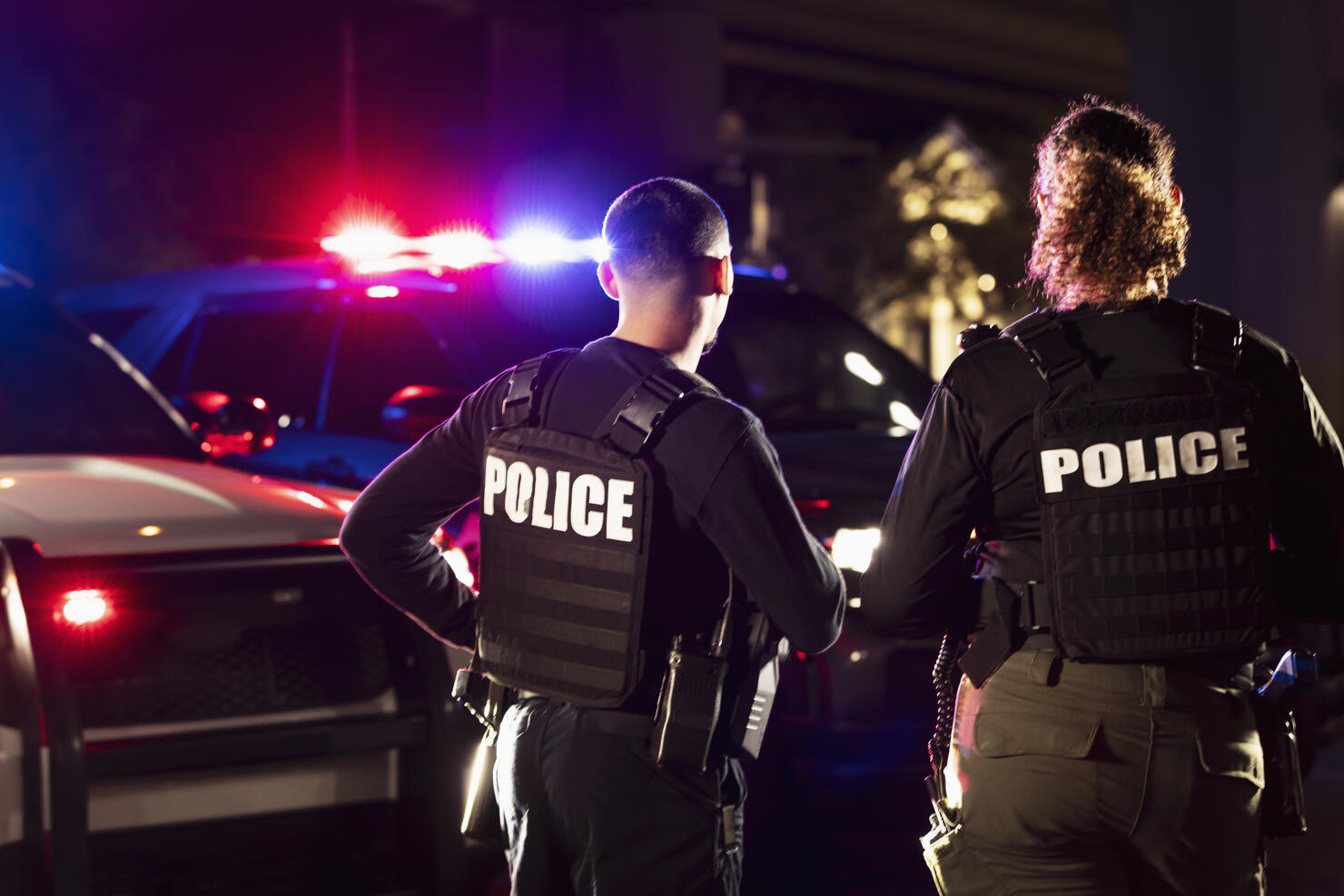 Two multiracial police officers working outdoors at night