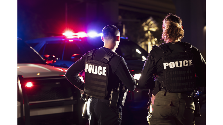 Two multiracial police officers working outdoors at night