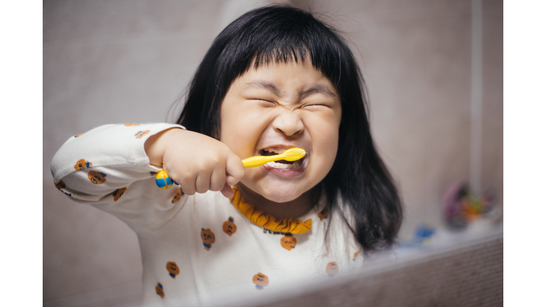 Happy little girl brushing her teeth in the bathroom