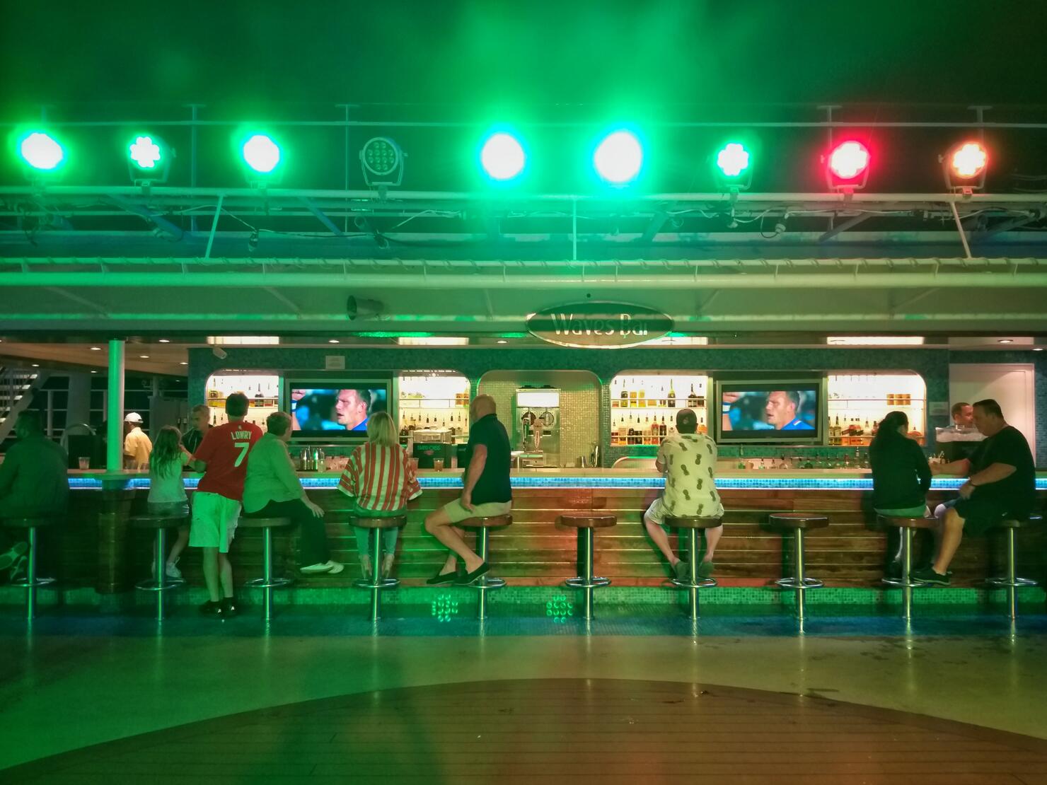 guests sitting at Waves Bar with the green night light on NCL Epic