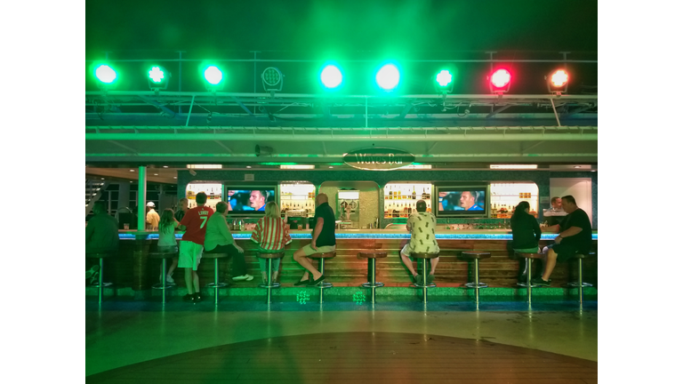 guests sitting at Waves Bar with the green night light on NCL Epic
