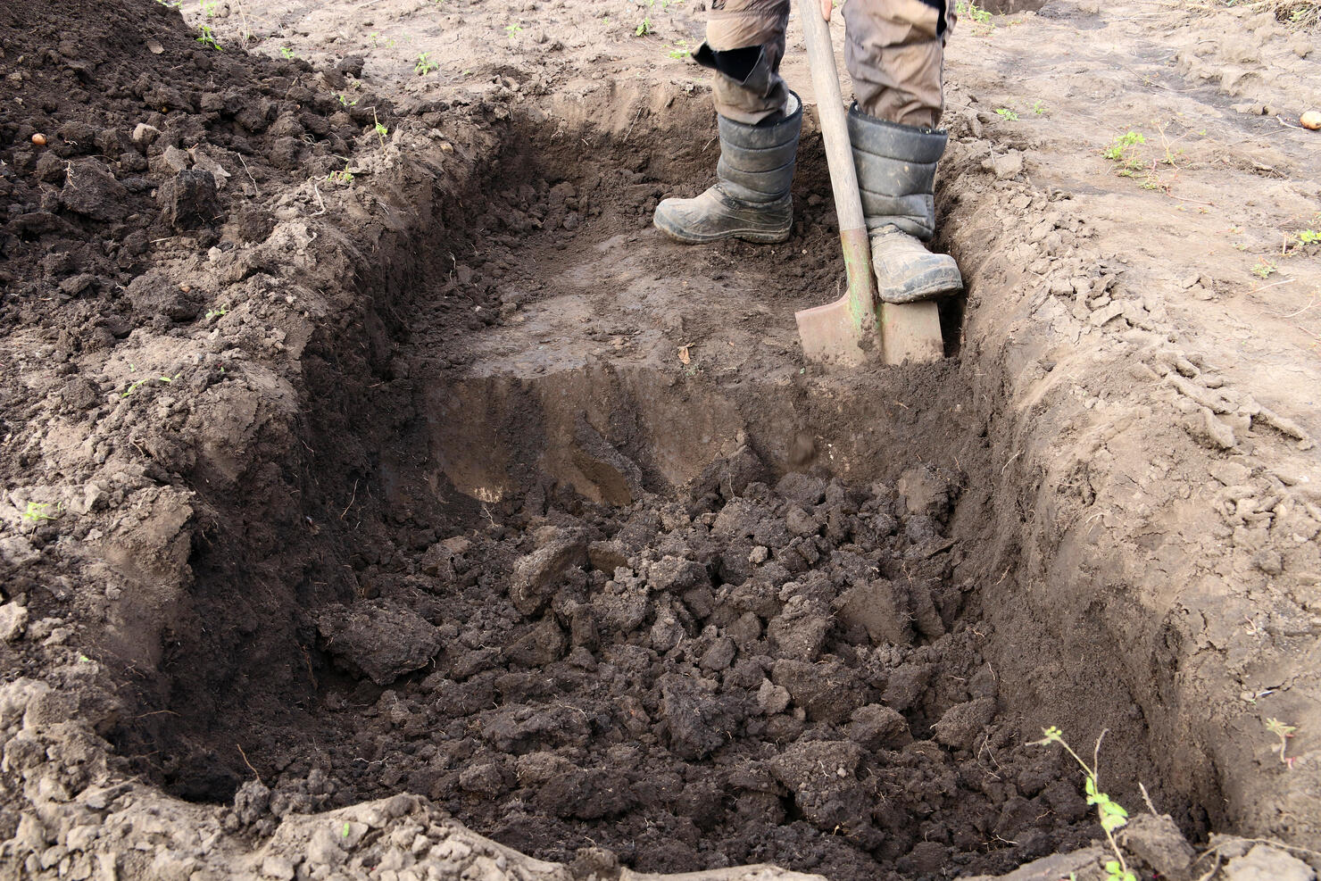 Man digs a deep pit. Digging a pit by shovel.