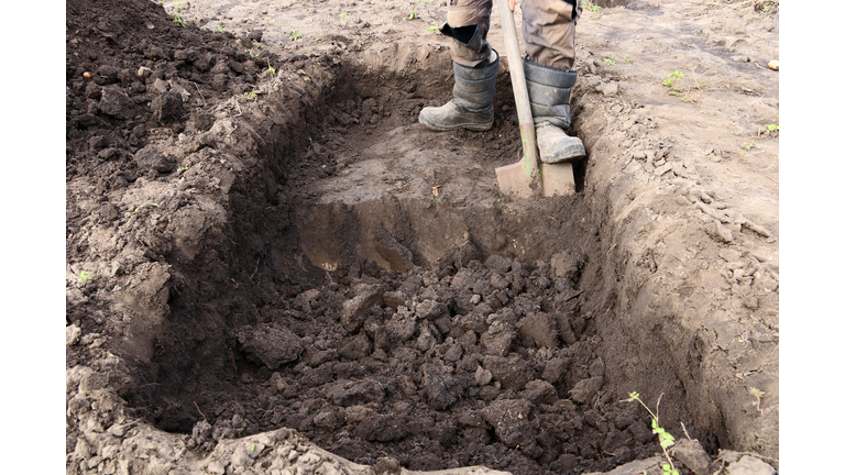 Man digs a deep pit. Digging a pit by shovel.