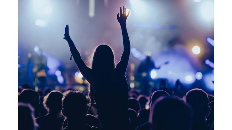 Silhouette of a woman with raised hands on a concert