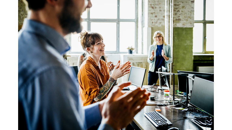 Business people applauding to colleague in office